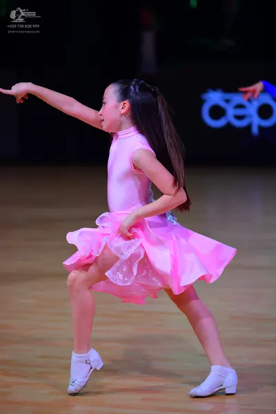 Dancesport competitor: Female dancer: pink sleeveless Latin dance dress with a high neck and a volumino