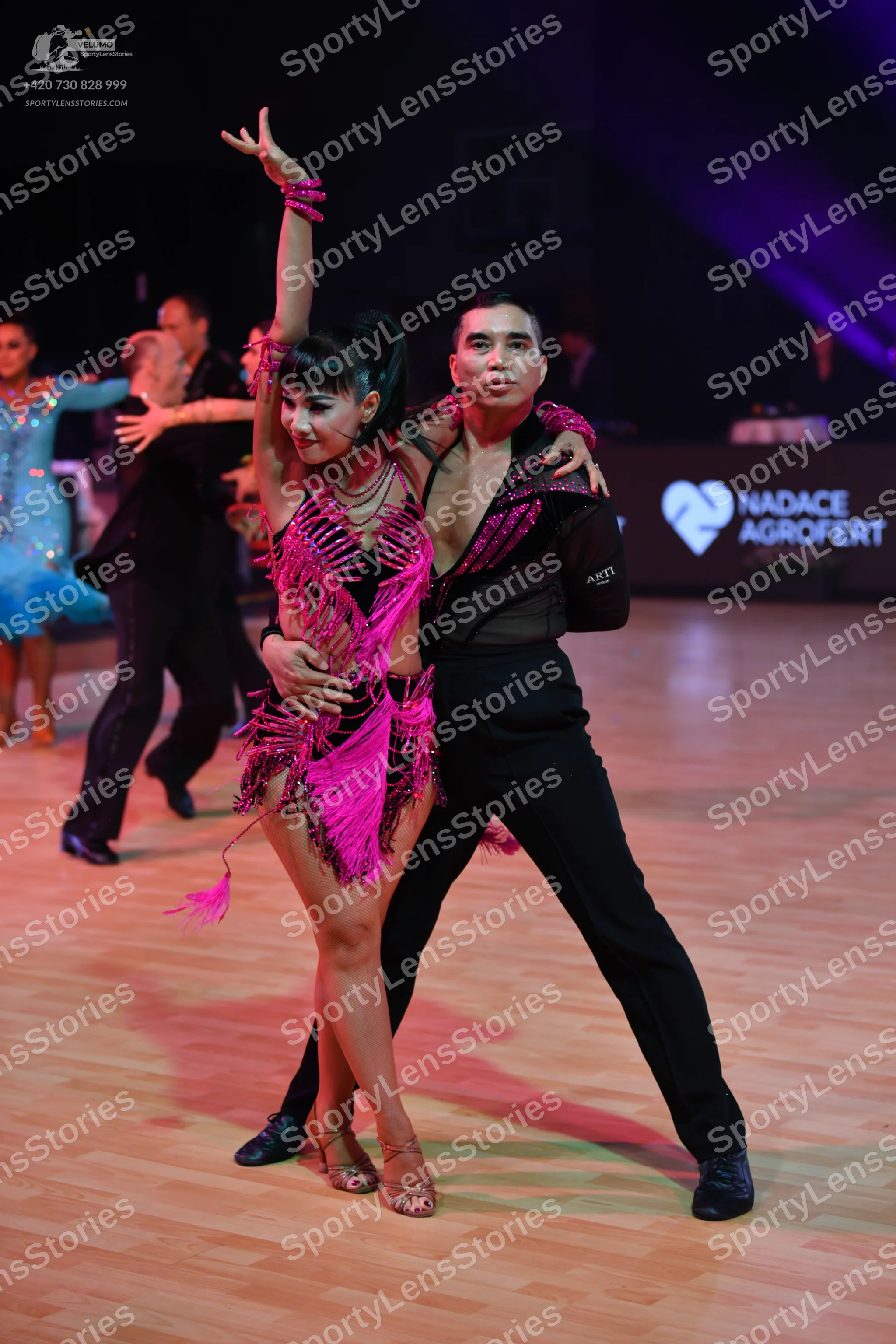Dancesport competitor: Female dancer in foreground: pink Latin dance dress with fringe and sequins