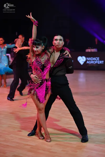 Dancesport competitor: Female dancer in foreground: pink Latin dance dress with fringe and sequins