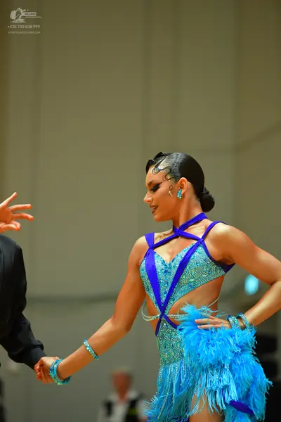 Dancesport competitor: Female dancer: turquoise latin dress with sequins, blue straps, and blue fringe,