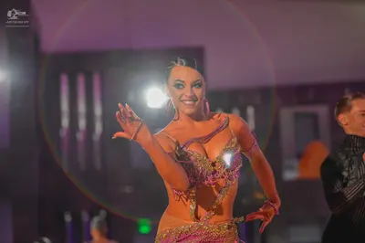 Dancesport competitor: Female dancer: nude-colored Latin dance costume heavily embellished with pink, p