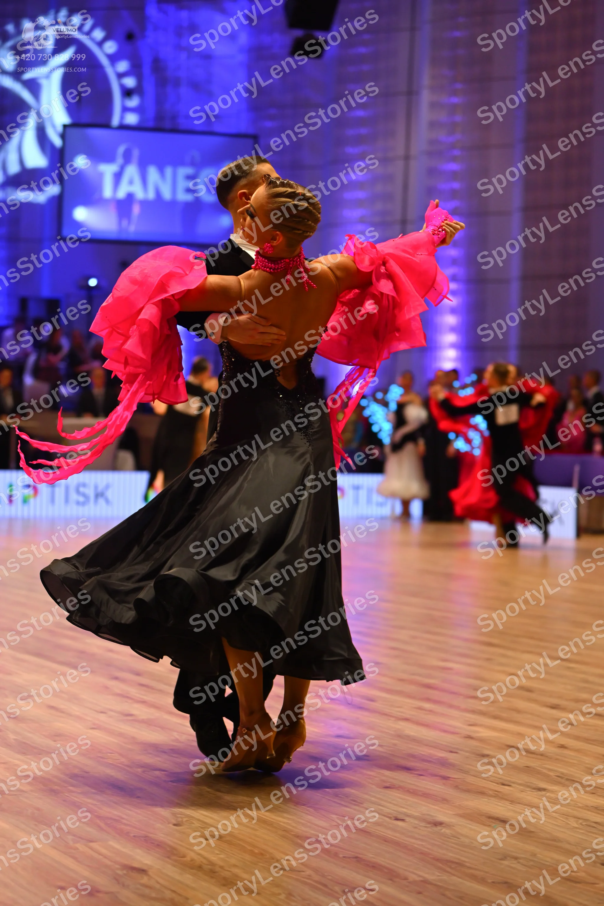 Dancesport competitor: Main female dancer: black ballgown with large, bright pink ruffled sleeves