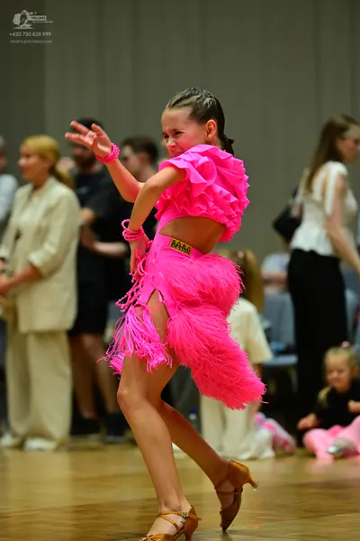 Dancesport competitor: Female dancer: bright pink Latin dance costume featuring a ruffled crop top and 