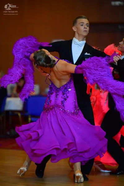 Dancesport competitor: Female dancer: purple Latin dance dress with sequin embellishments, a layered/ru