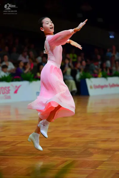 Dancesport competitor: Female dancer: light pink ballroom dress with long sleeves and a flowing skirt