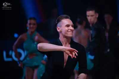Dancesport competitor: Male dancer in foreground: black long-sleeved Latin dance top with a deep V-neck