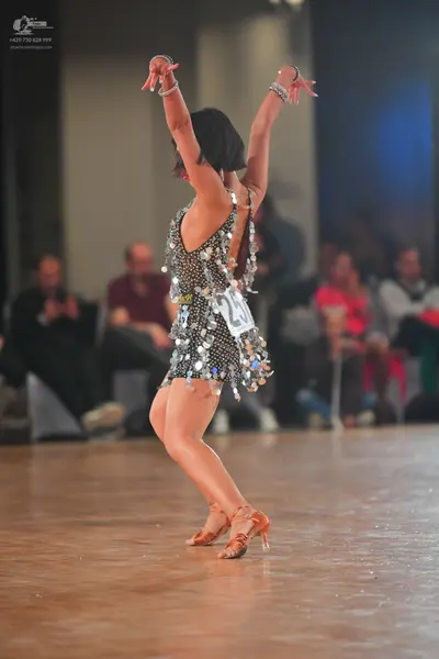 Dancesport competitor #27: Female dancer: short, dark Latin dress heavily embellished with large, reflectiv