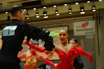 Dancesport competitor: Male dancer (foreground): black long-sleeved shirt with black fringe detailing o