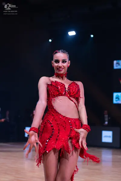 Dancesport competitor: Female dancer: red latin dress with sequins and fringe, including matching red w