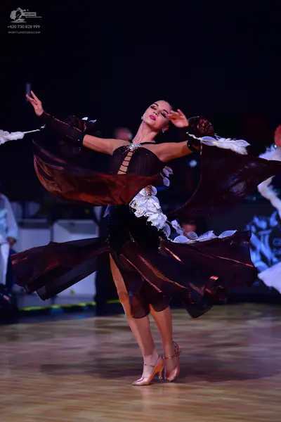 Dancesport competitor: Female dancer: dark burgundy flowing Latin dance dress with large, dramatic, ruf