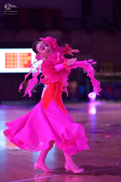 Dancesport competitor: Female dancer: bright pink Latin dance dress with voluminous ruffled sleeves and