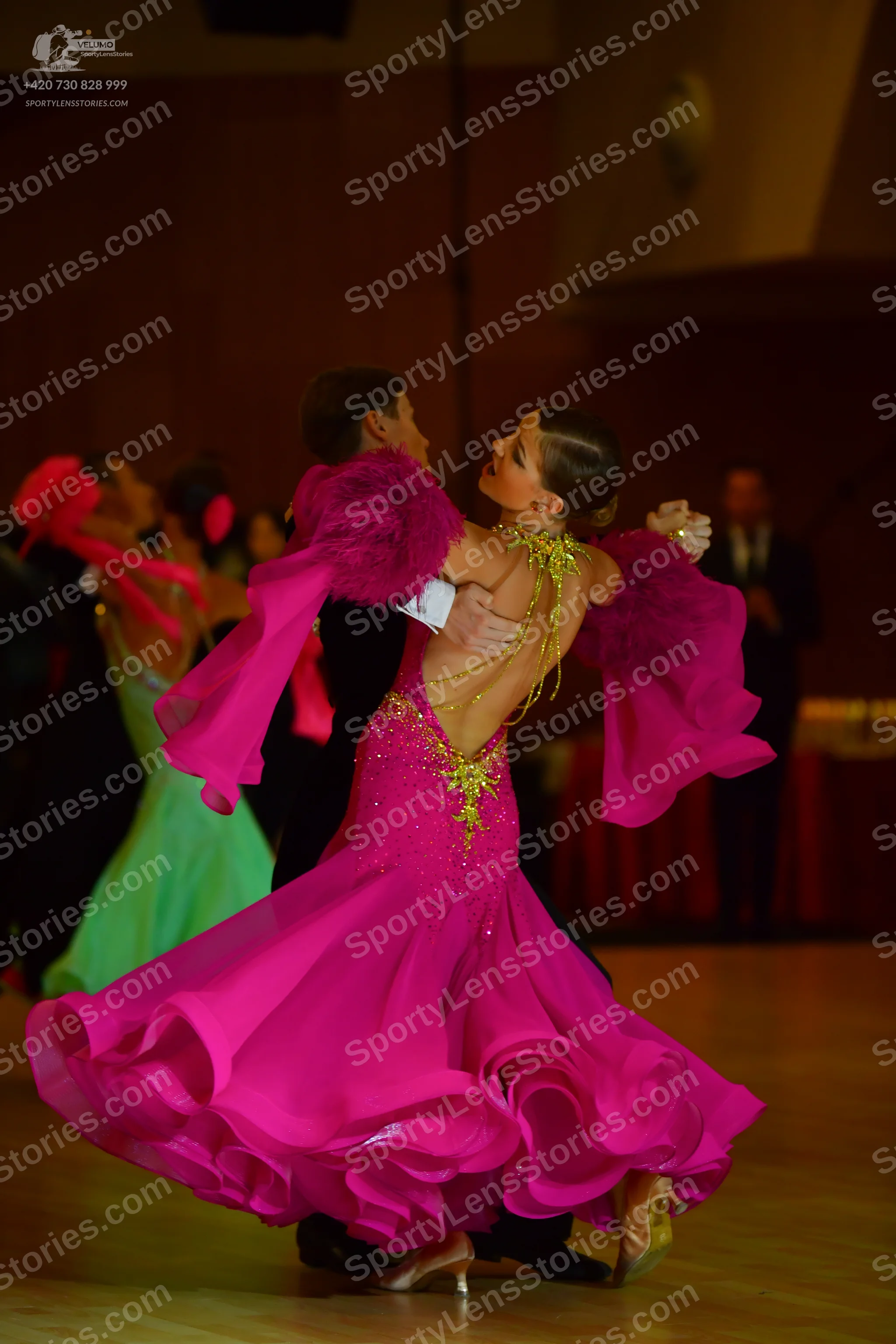 Dancesport competitor: Female dancer: bright pink ballroom gown with large, voluminous sleeves and gold