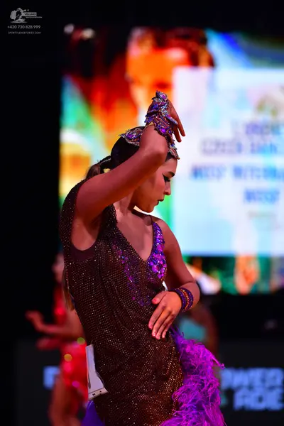 Dancesport competitor: Female dancer: dark brown/bronze sequined Latin dress with purple/blue sequined 