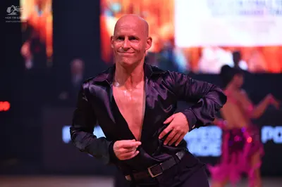 Dancesport competitor: Male dancer: black satin long-sleeved shirt, unbuttoned, and black trousers with