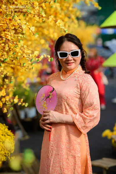 Dancesport competitor: Female dancer: peach-colored, long-sleeved patterned Ao Dai, accessorized with w