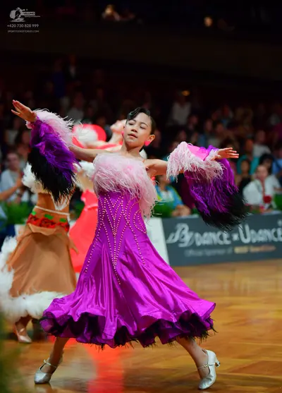 Dancesport competitor: Foreground dancer: fuchsia satin ballroom dress with pink and dark purple feathe