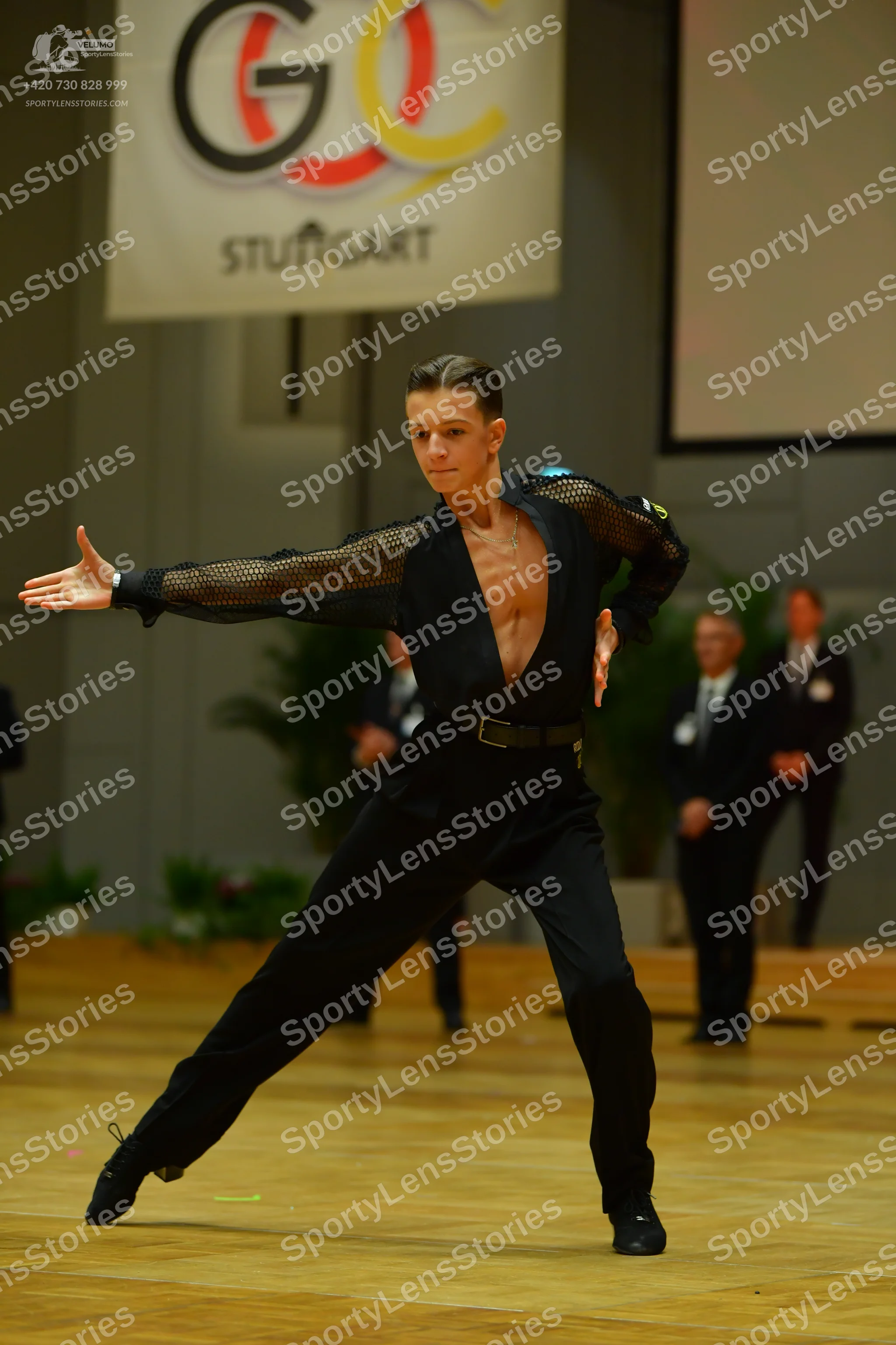 Dancesport competitor: Female dancer: black, form-fitting, long-sleeved costume with a deep V-neckline