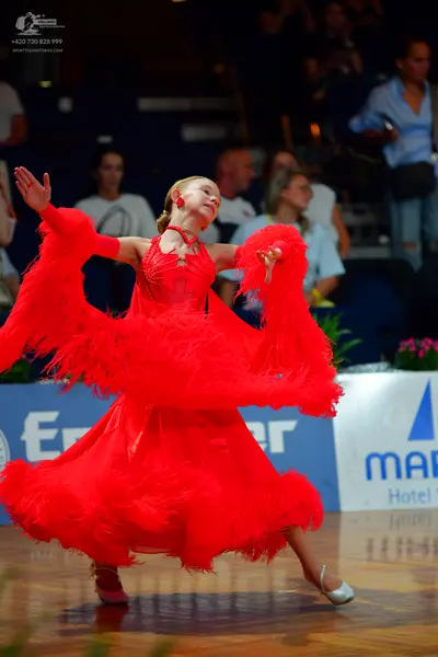 Dancesport competitor: Female dancer: bright red, voluminous ballroom dance dress with layered ruffles 