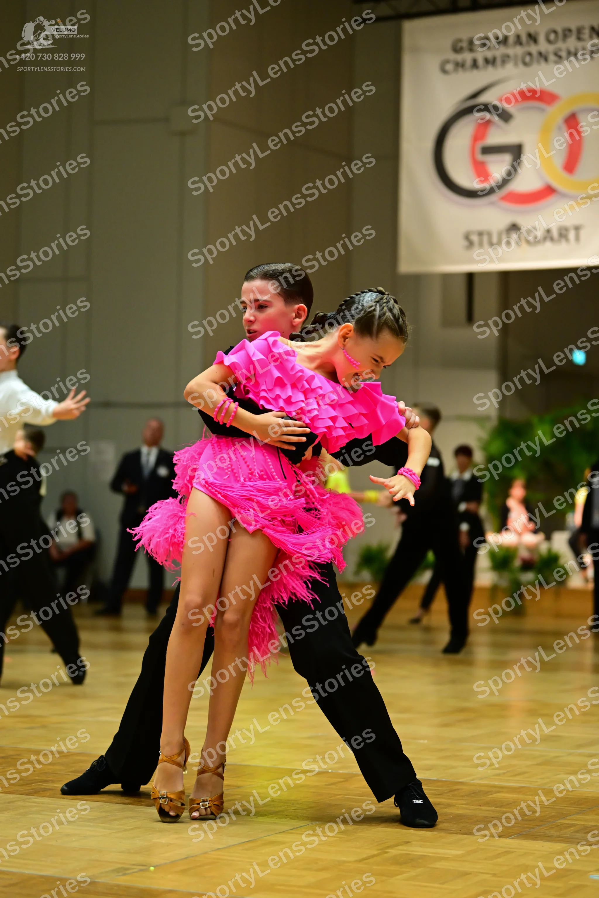 Dancesport competitor: Main female dancer: bright pink latin dress with layered ruffles and fringe