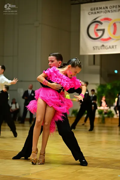 Dancesport competitor: Main female dancer: bright pink latin dress with layered ruffles and fringe