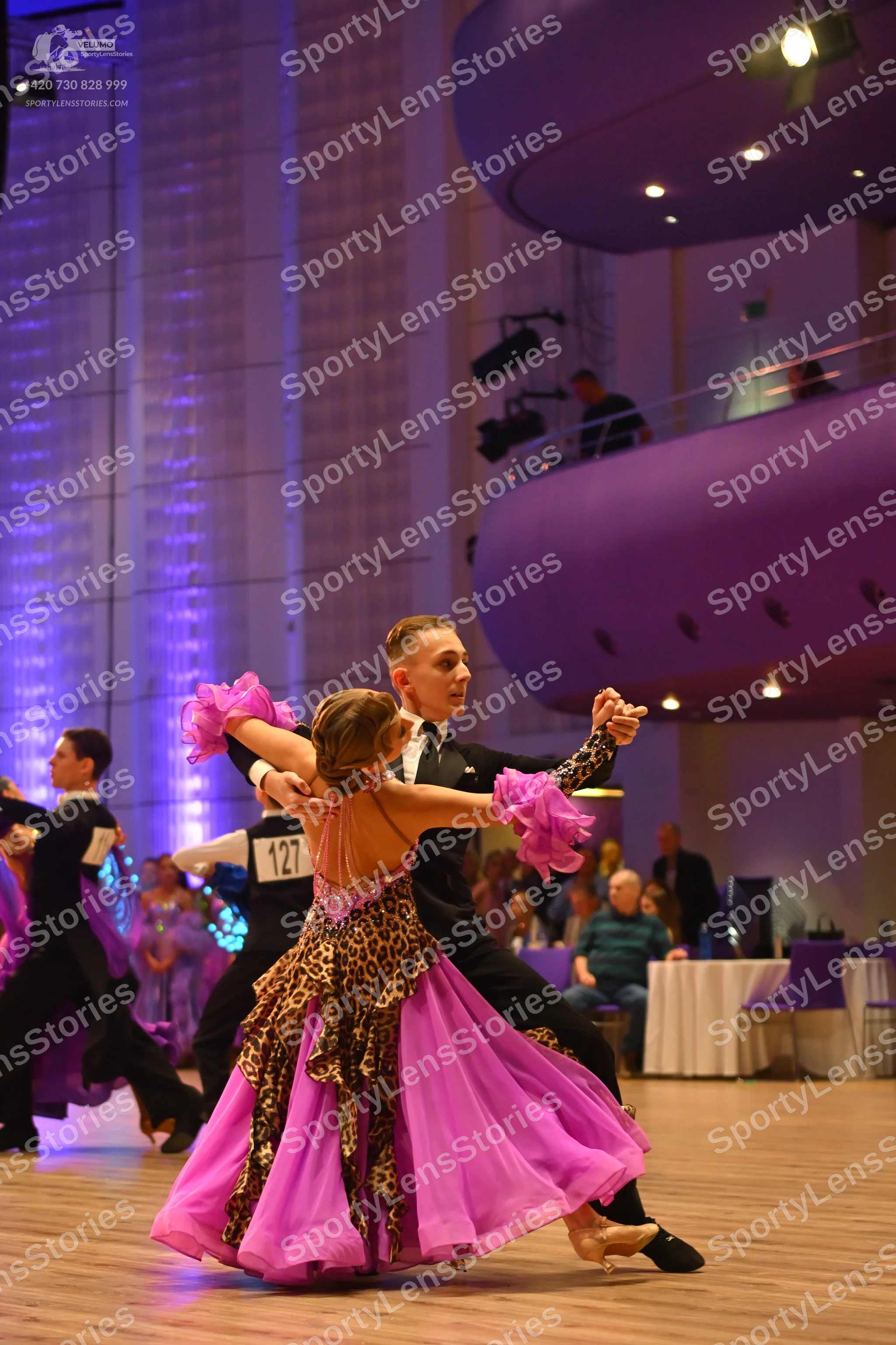 Dancesport competitor: Female dancer: pink latin dress with leopard print pattern and a sheer, flowing 