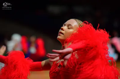 Dancesport competitor: Female dancer: bright red Latin dance dress with voluminous red feathers