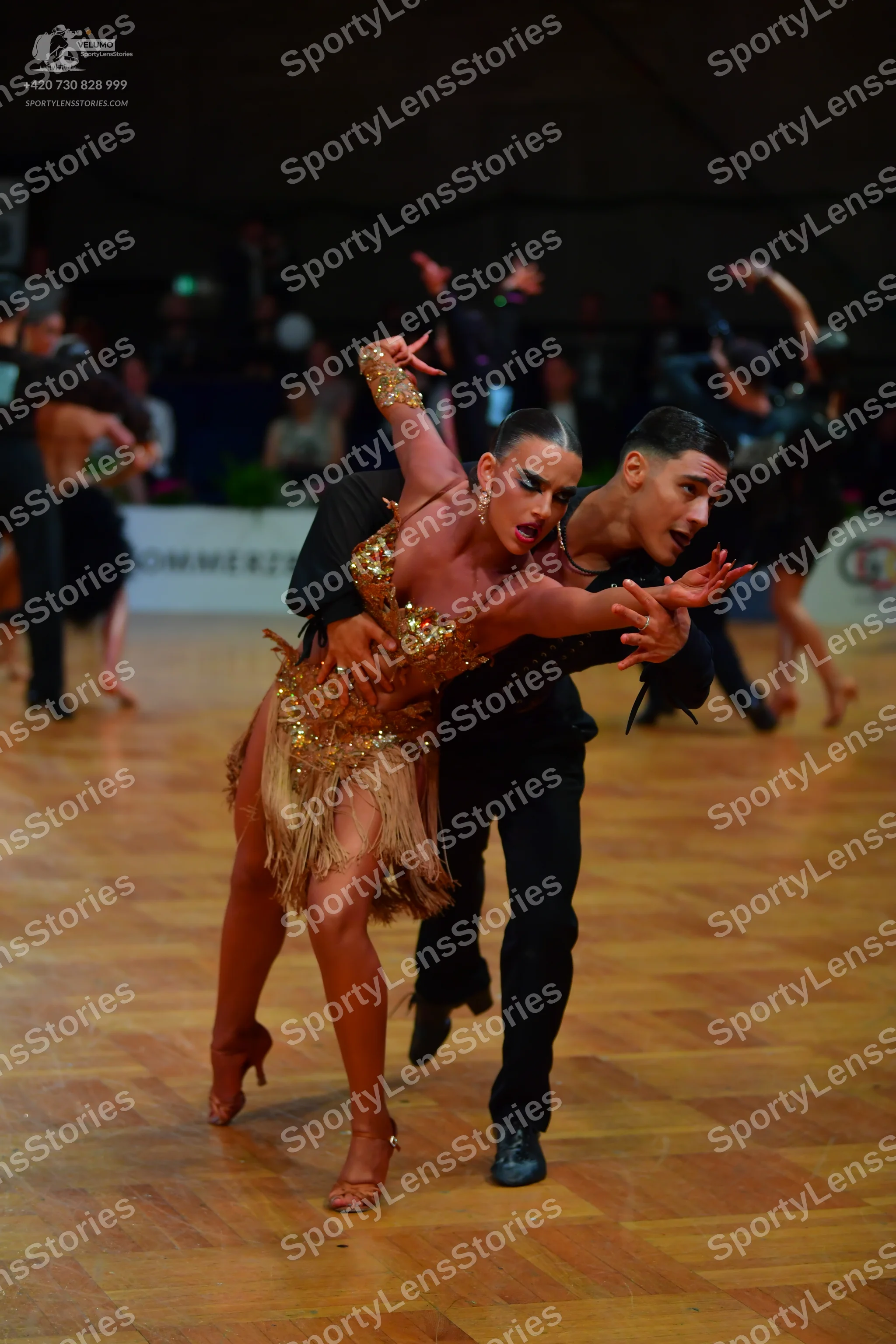 Dancesport competitor: Female dancer: gold/bronze Latin dance dress featuring extensive sequin embellis