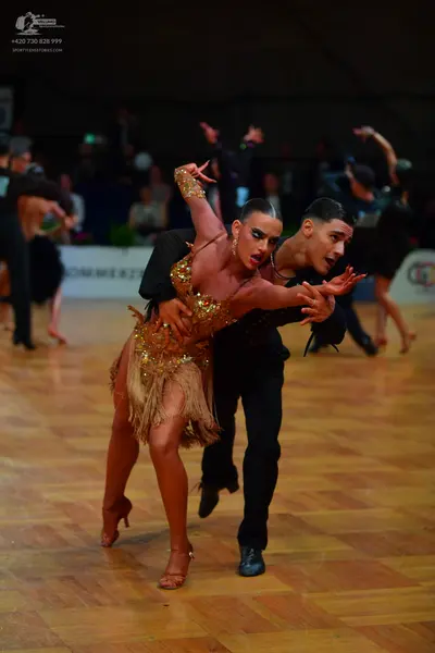 Dancesport competitor: Female dancer: gold/bronze Latin dance dress featuring extensive sequin embellis