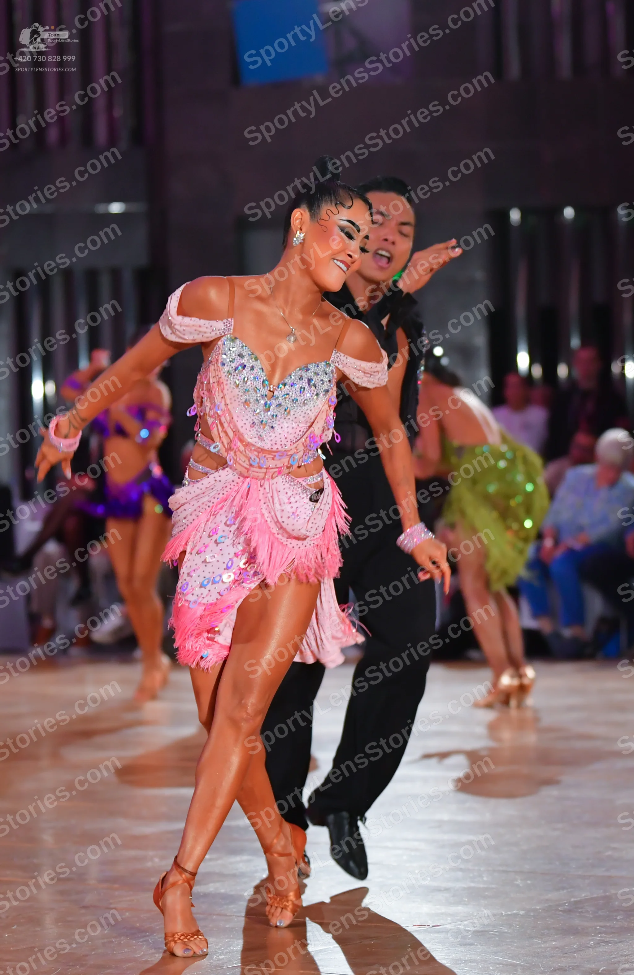 Dancesport competitor: Main female dancer: pink Latin dress with sequins, beads, and fringe, featuring