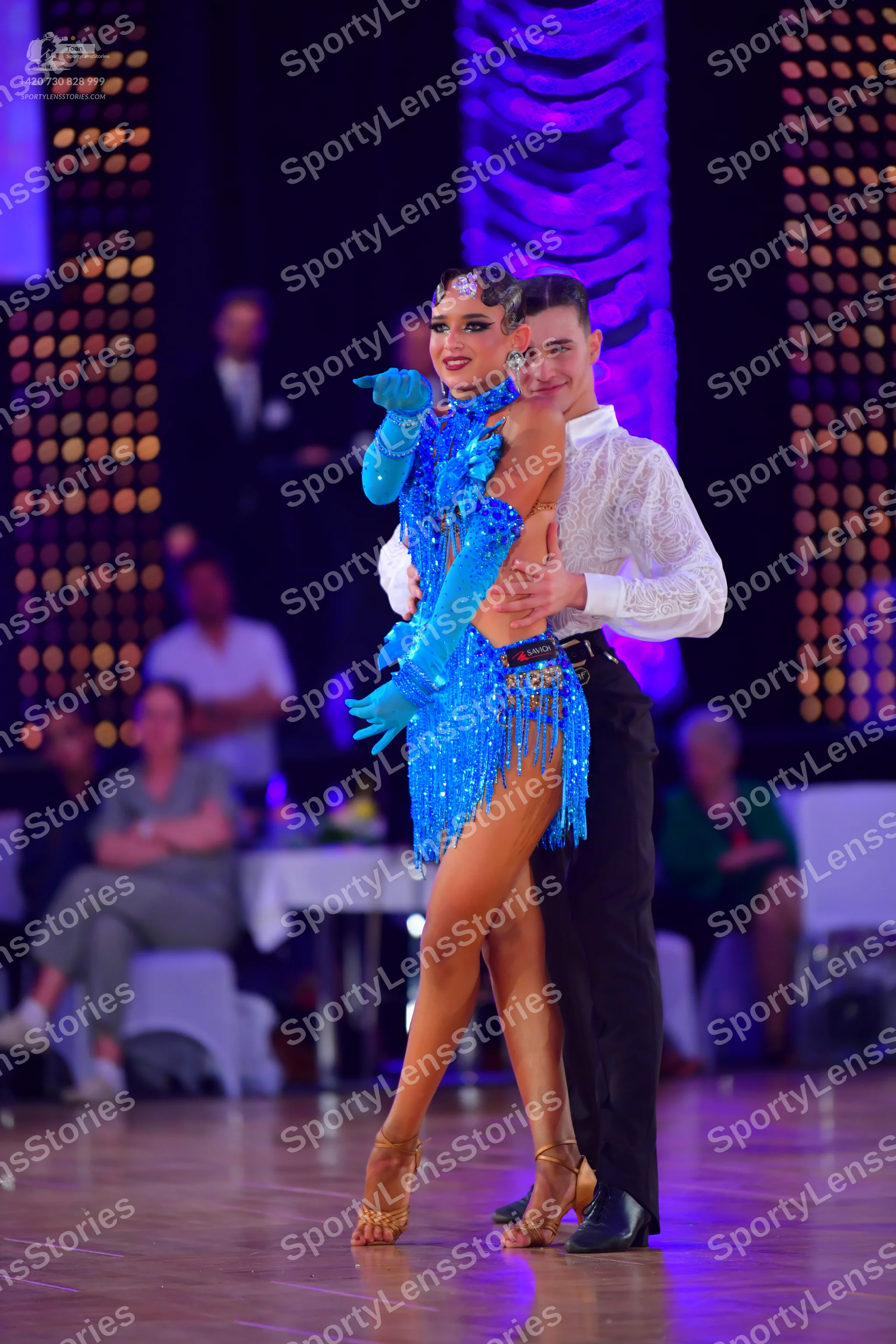 Dancesport competitor: Female dancer: blue sequined Latin dress with fringe and matching long blue glov