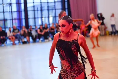 Dancesport competitor: Female dancer in foreground: leopard print latin dress with black fringe and thi