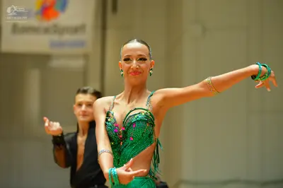Dancesport competitor: Female dancer: green latin dress with sequins and fringe, wearing green bracelet