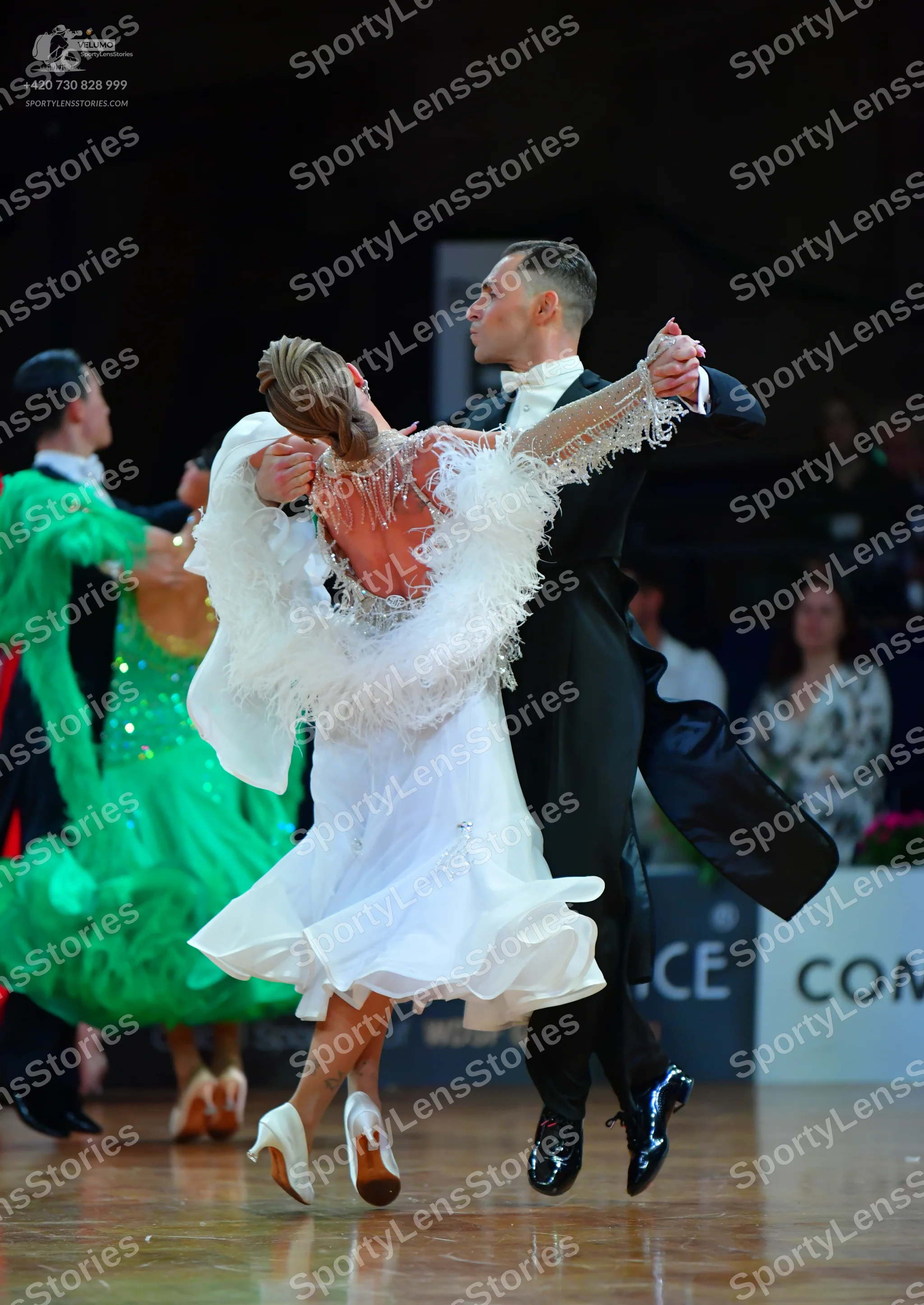Dancesport competitor: Male dancer in foreground: black ballroom suit with a white shirt and white bow