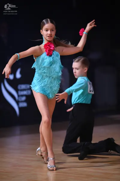 Dancesport competitor: Female dancer: turquoise latin dress with fringe texture and a pink flower acces