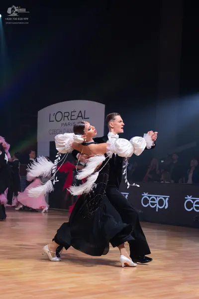 Dancesport competitor: Female dancer: black ballroom dress with large, voluminous, white feathery sleev