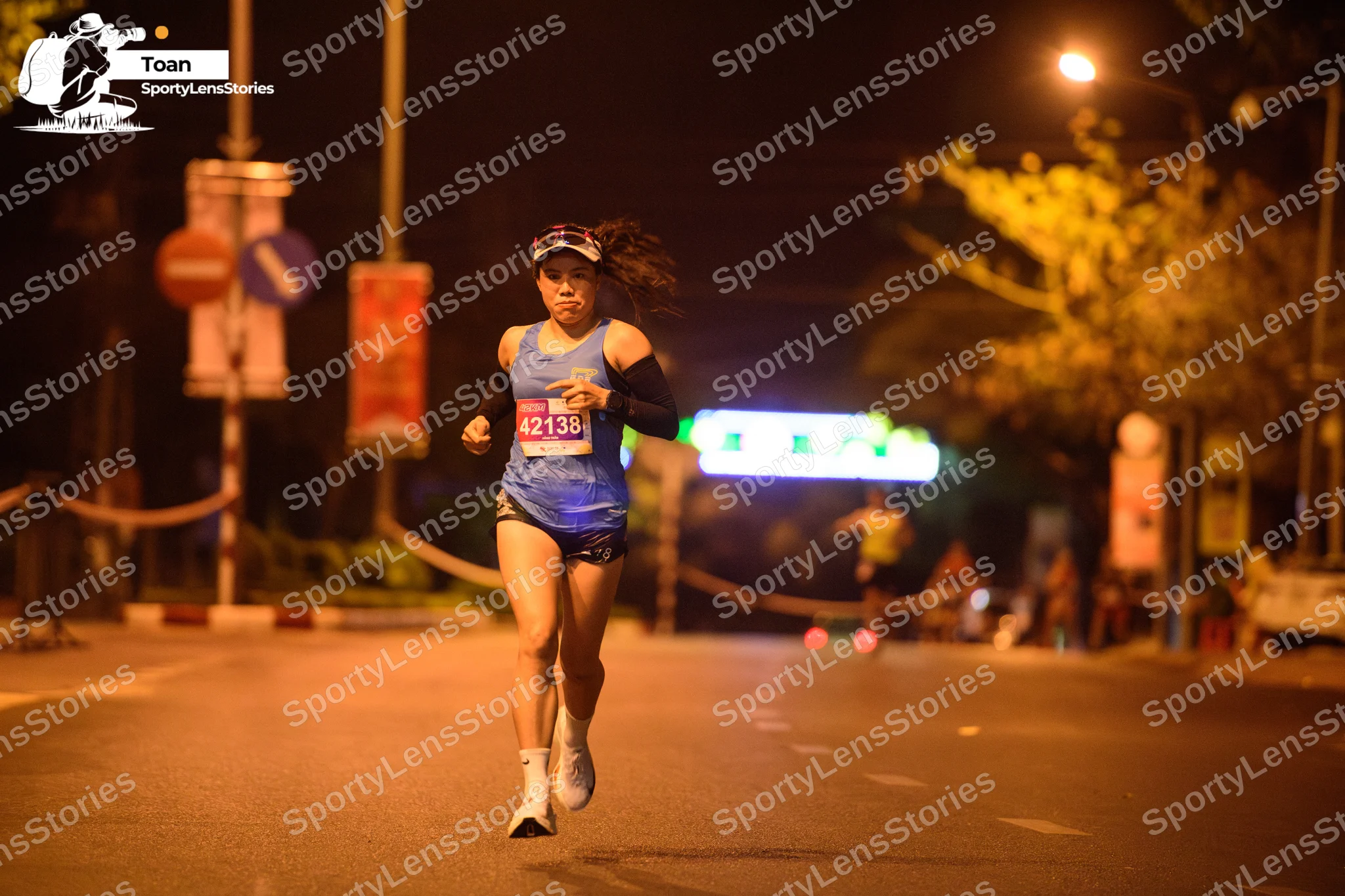 Marathon runner #42138: Runner 1: blue tank top, black shorts, white shoes, white headband, and black ar