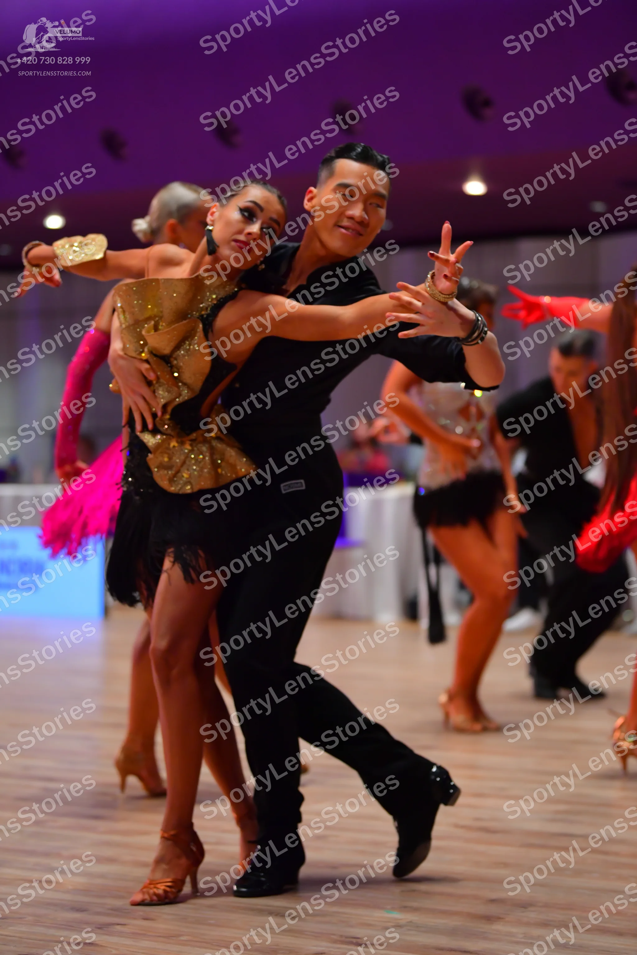 Dancesport competitor: Main female dancer: gold sequin bodice, black fringe skirt, and a gold cuff acce