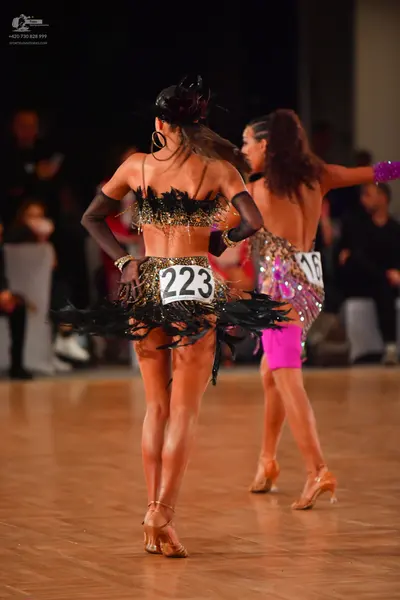 Dancesport competitor #223, #16: Female dancer 1: black and gold latin dance dress with sequins, black fringe, an
