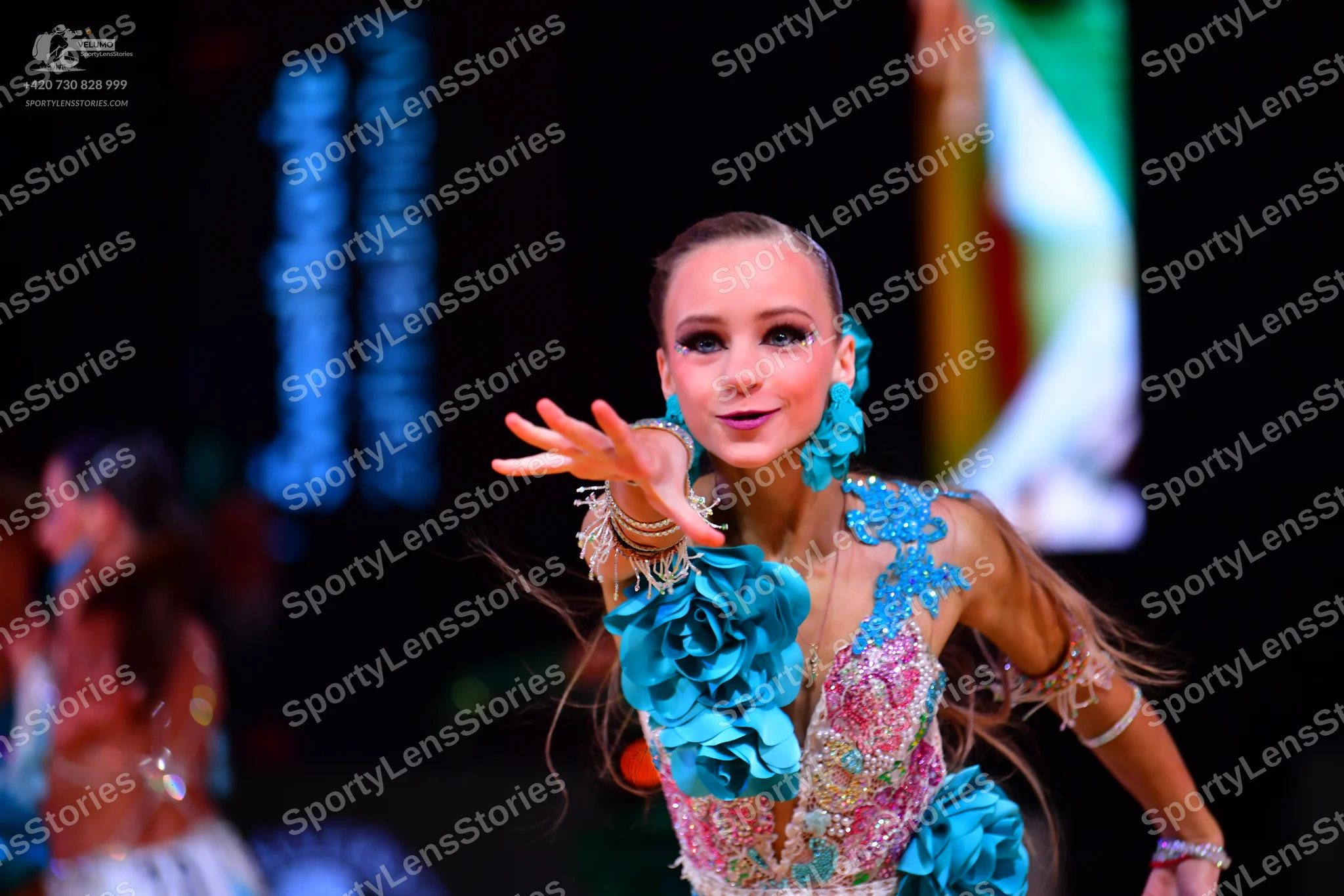 Dancesport competitor: Female dancer in foreground: Turquoise and light pink latin dance dress embellis