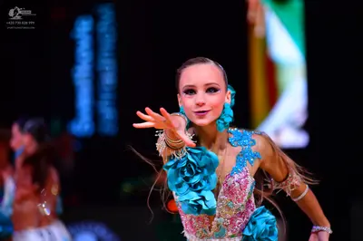 Dancesport competitor: Female dancer in foreground: Turquoise and light pink latin dance dress embellis
