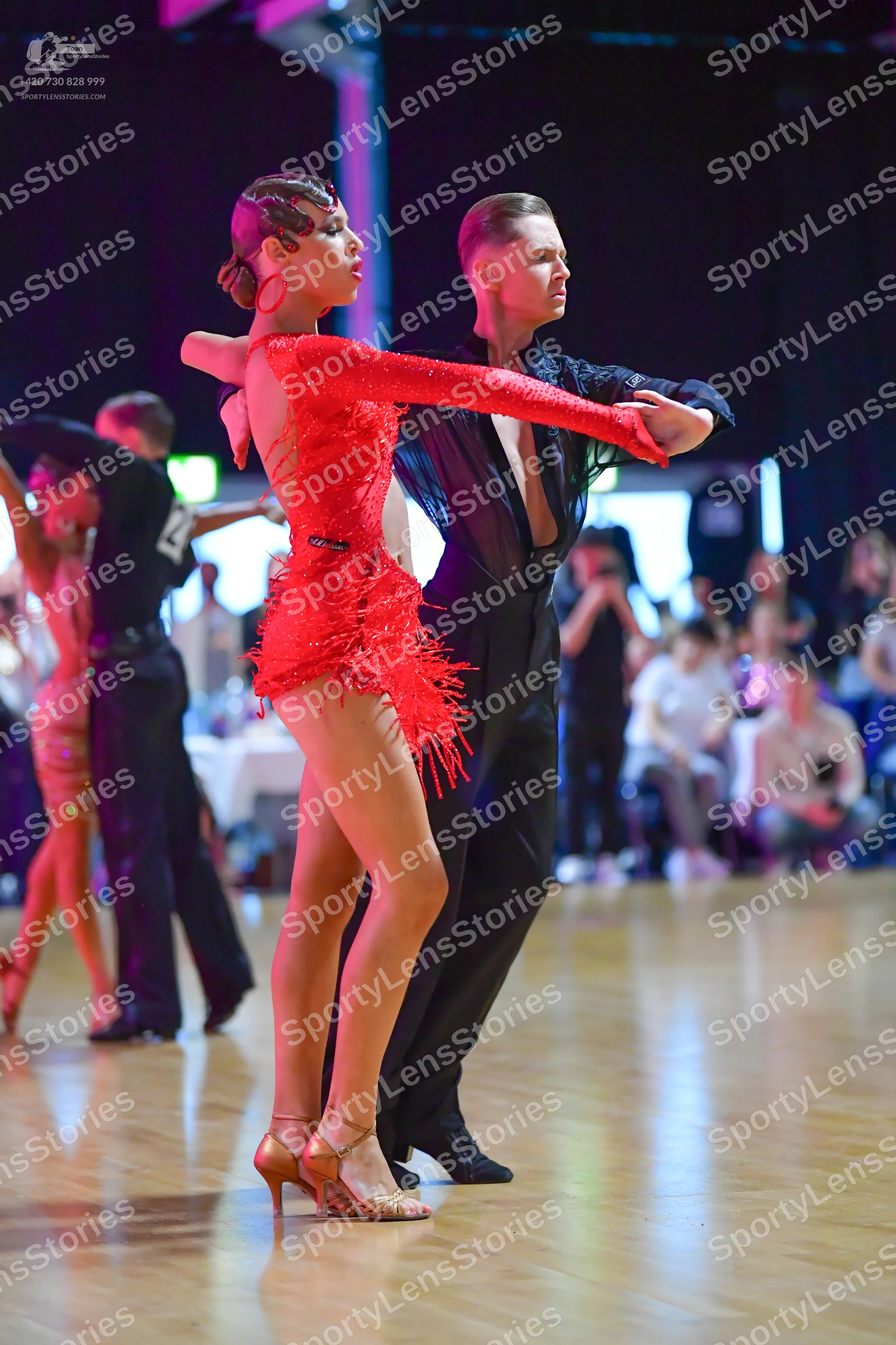 Dancesport competitor: Female dancer: red Latin dress with long sleeves and fringe