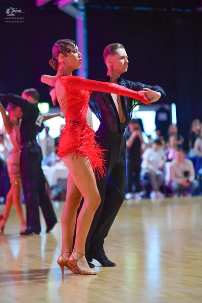 Dancesport competitor: Female dancer: red Latin dress with long sleeves and fringe