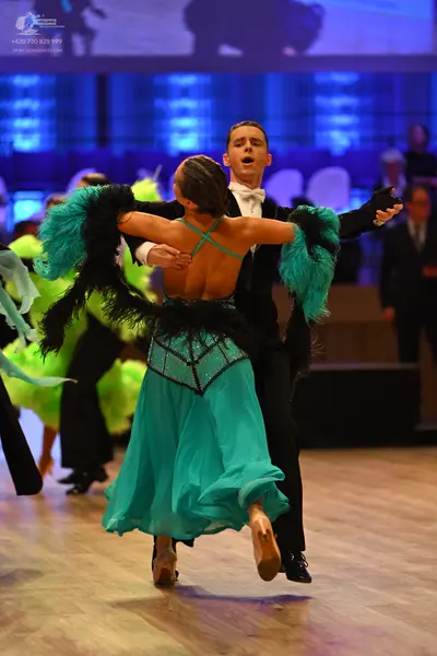 Dancesport competitor: Female dancer: teal latin dress with a black sequined bodice and large teal and 