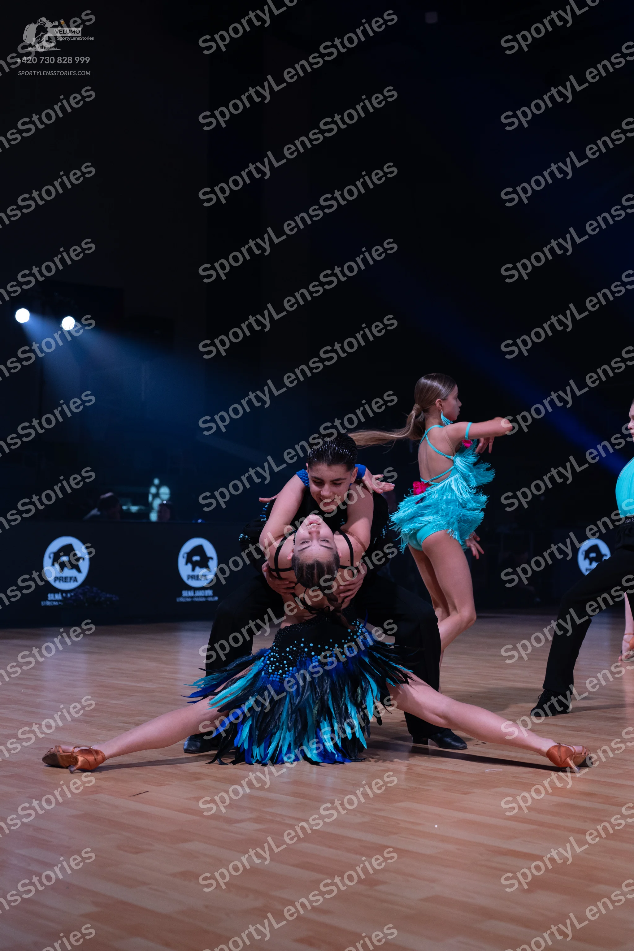 Dancesport competitor: Female dancer in foreground: dark blue and black Latin dance dress with a skirt