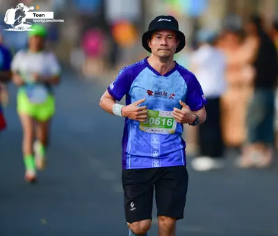 Marathon runner #50616: Runner 1: blue/purple jersey, black shorts, black bucket hat, white wristband