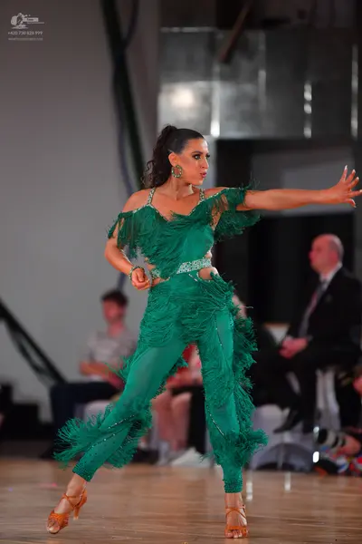 Dancesport competitor: Female dancer: emerald green Latin dance jumpsuit with heavy fringe detailing on