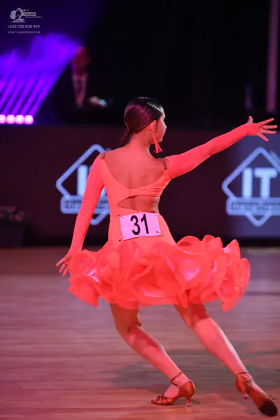 Dancesport competitor: Female dancer: peach-colored latin dress with long sleeves, an open back, and a 
