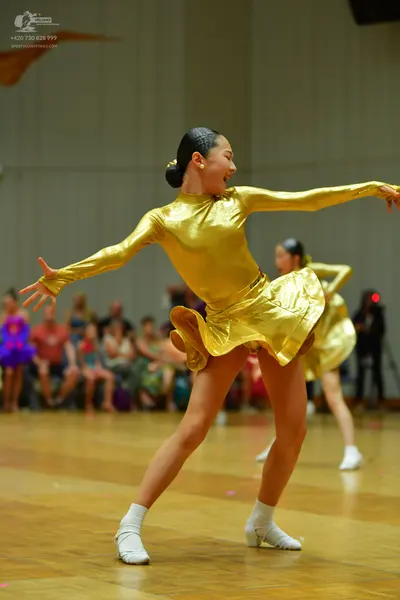 Dancesport competitor: Female dancer: gold satin latin dress with long sleeves
