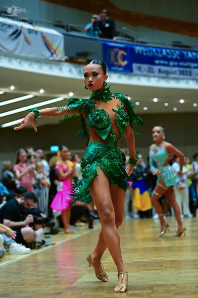 Dancesport competitor: Female dancer 1: green Latin dress with sequins and fringe