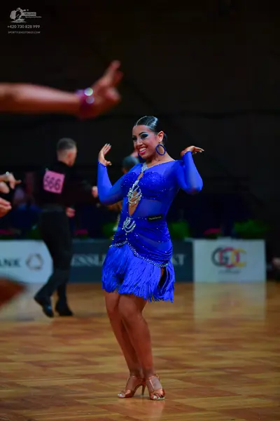 Dancesport competitor: Female dancer: blue latin dress with sequins, fringe, and long sleeves, accessor